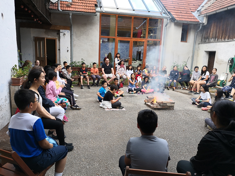 德威和德闳学生在围坐在营火旁吃棉花糖唱歌